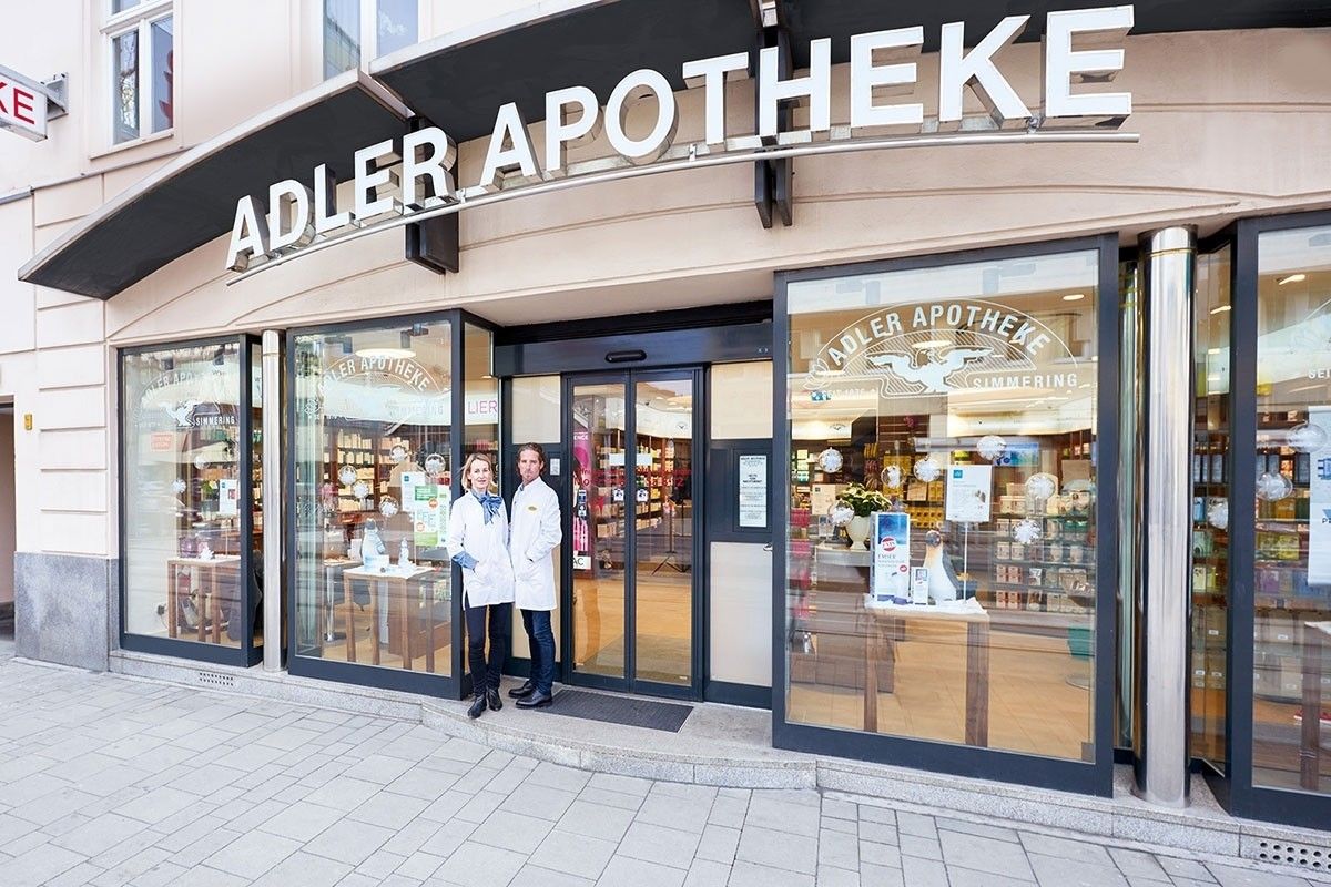 Zwei Mitarbeiter stehen vor dem Eingang einer Apotheke.