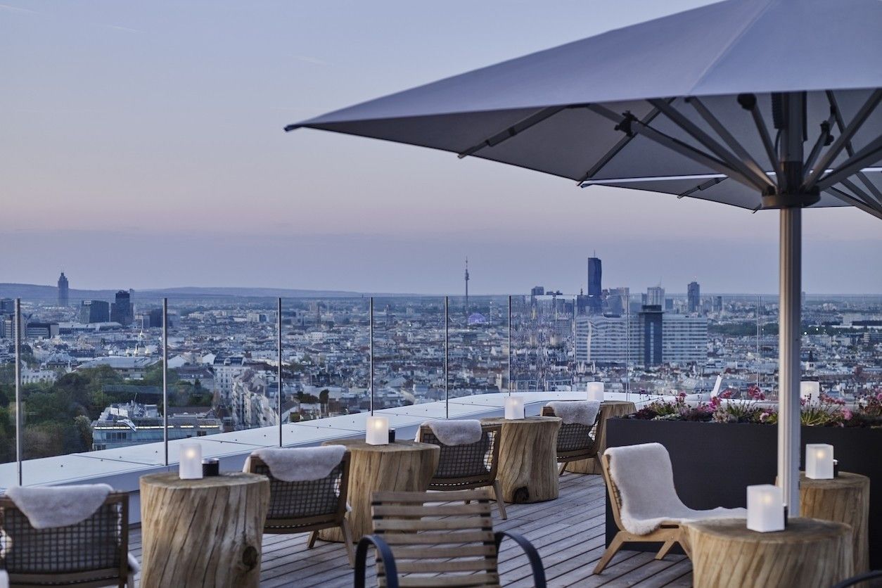 Rooftop Terrasse mit einem Schirm und vielen Stühlen und Tischen