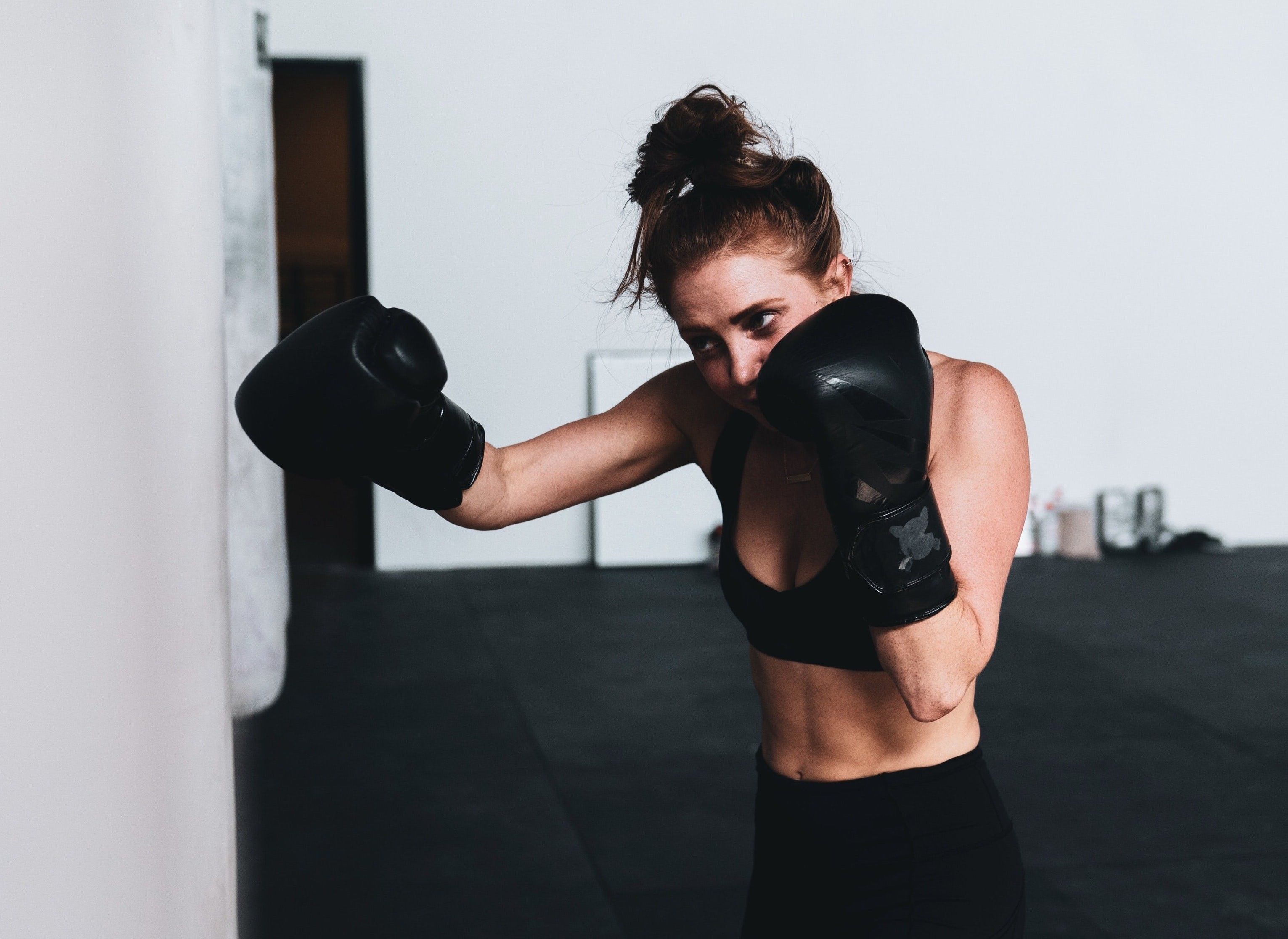 Eine Frau in Sportkleidung mit Boxhandschuhen boxt gegen einen Boxsack