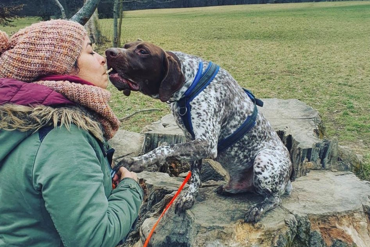 Eine Frau und ein Hund. Der Hund frisst der Frau aus dem Mund