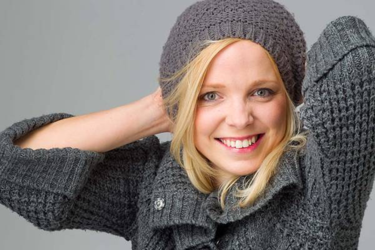 Eine Frau mit blonden Haaren und einer Grauen Mütze und Pullover