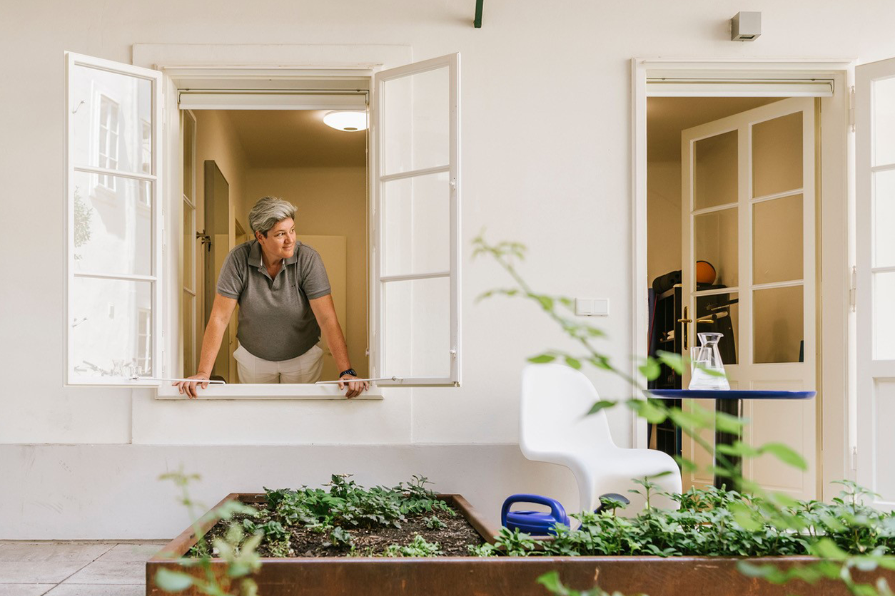 Eine Frau schaut aus einem Fenster in einen Innenhof