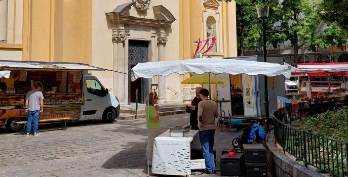 Marktplatz vor der Kirche mit Standl und Menschen