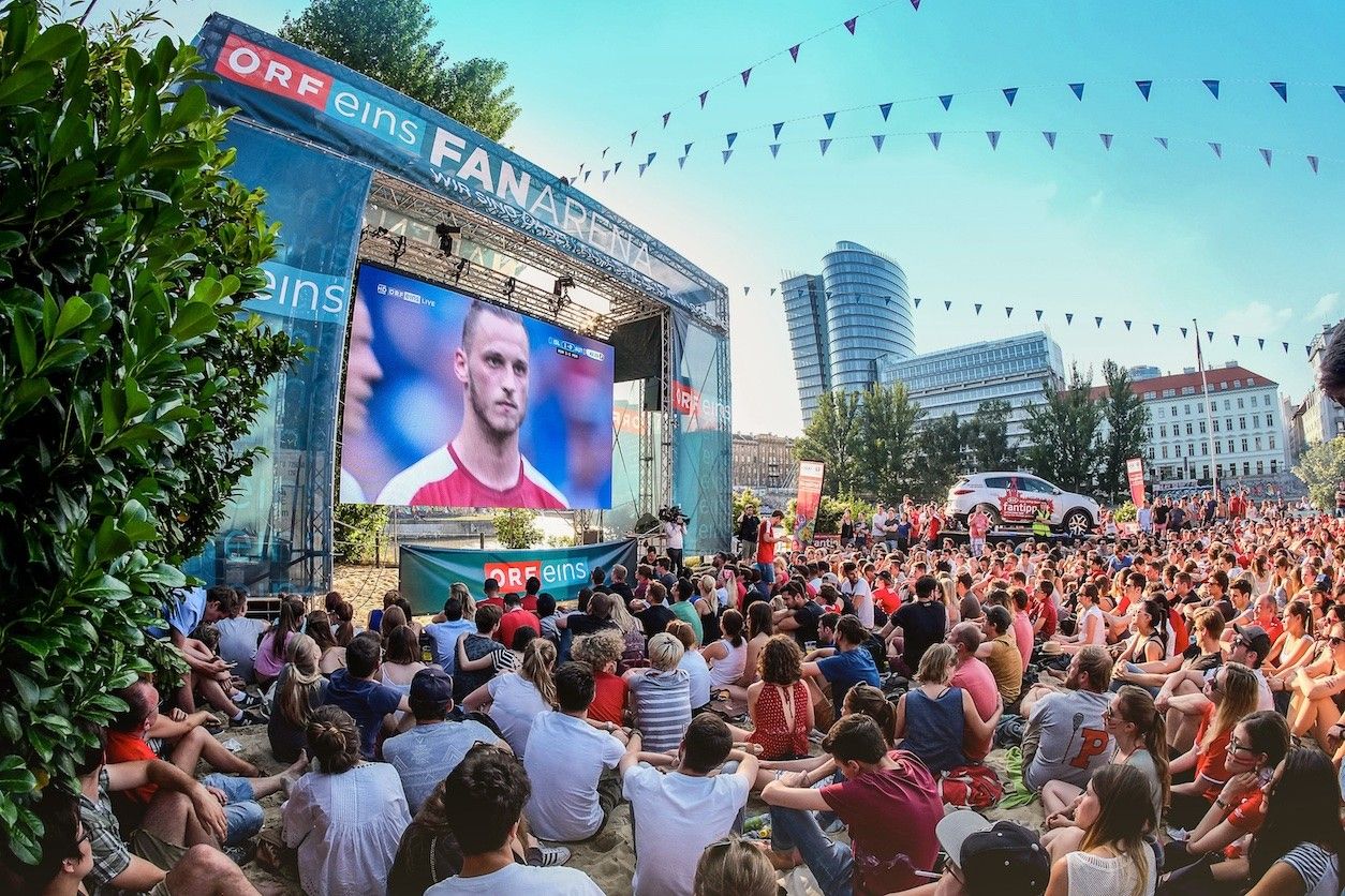 Public Viewing mit einer Leinwand und vielen Menschen.