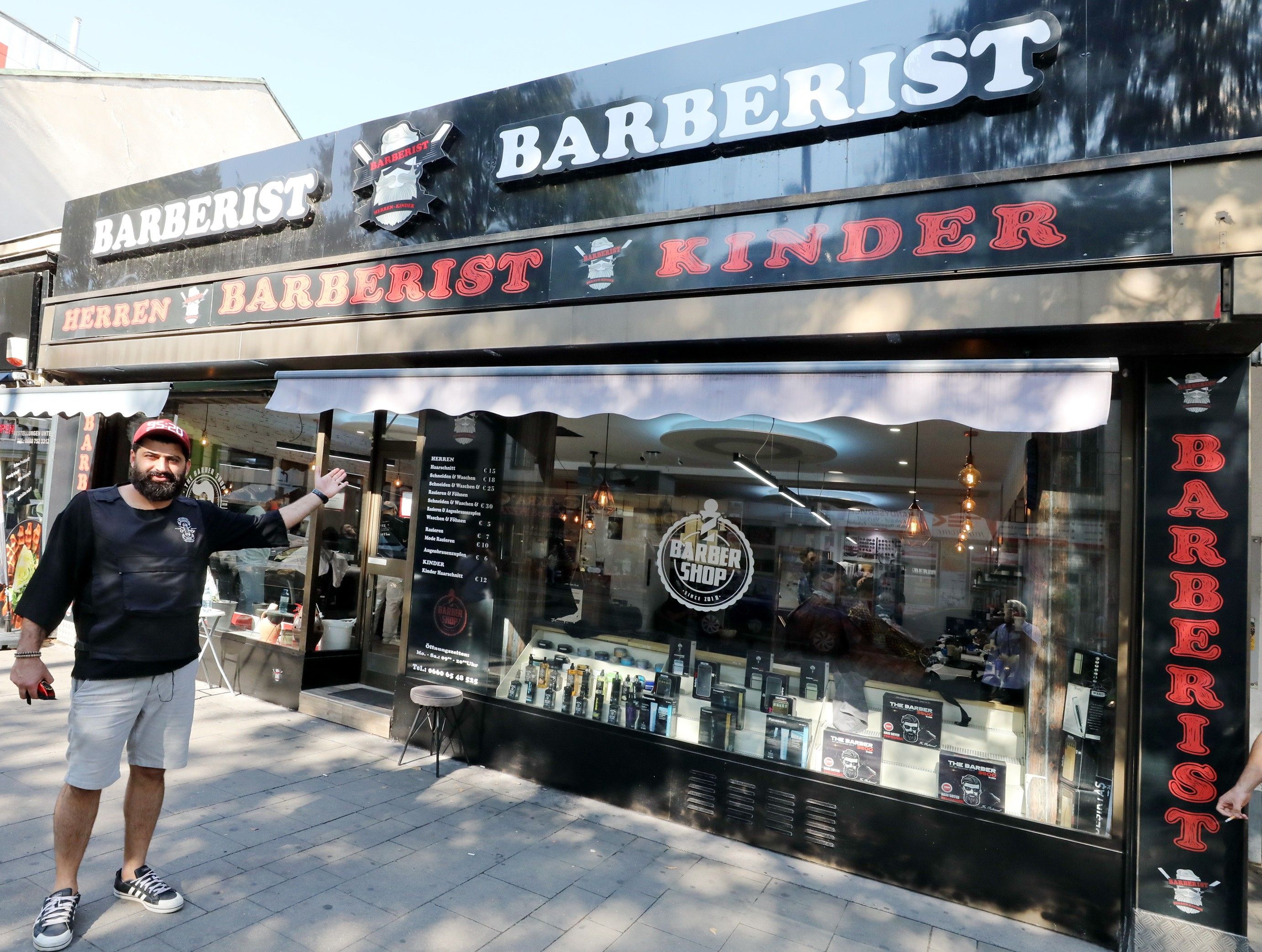 Eingangsbereich des Barberist Friserusalons mit Mann der der auf die Auslange des Salons zeigt