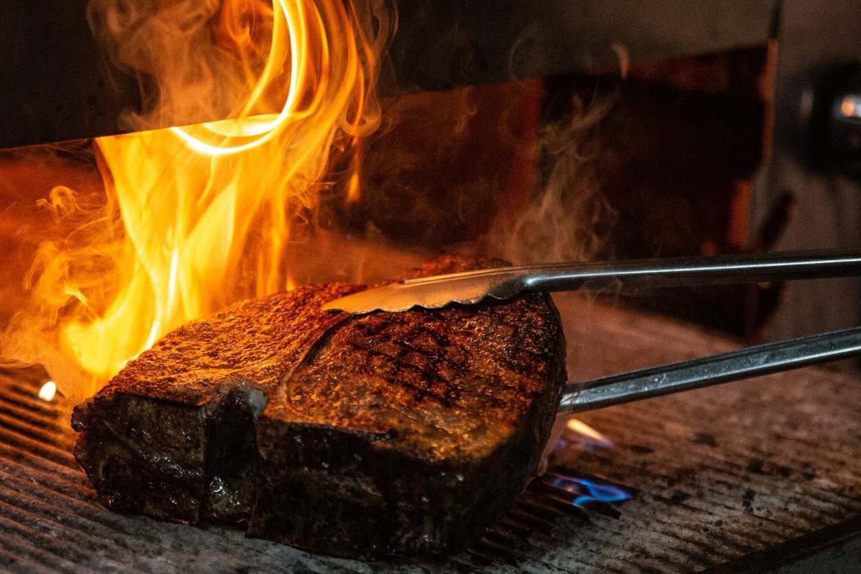 Ein Steak auf einem Grill mit Flammen