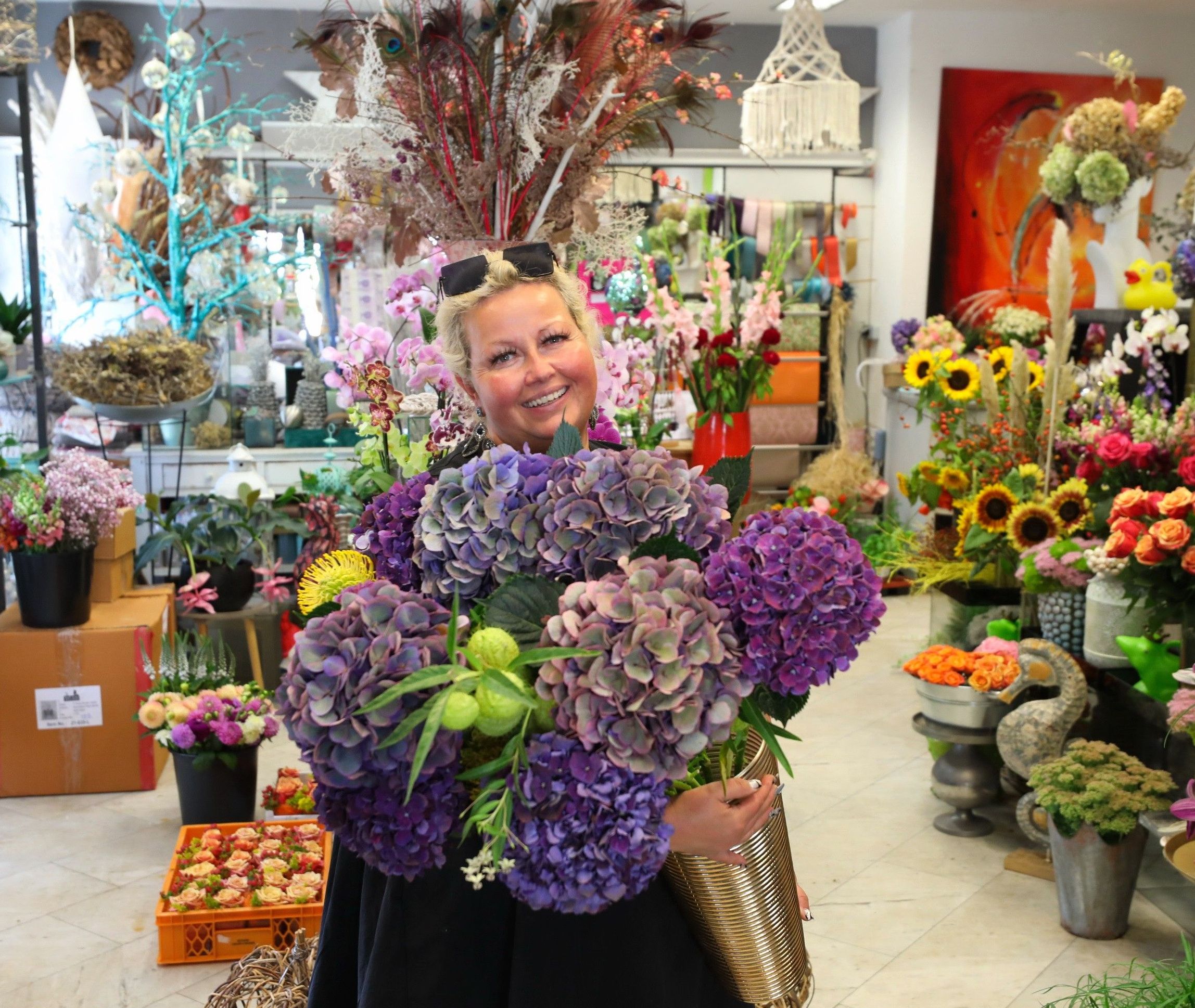 Innenbereich des Blumengeschäfts Blütenzeit mit Frau, die Blumen in der Hand hält.