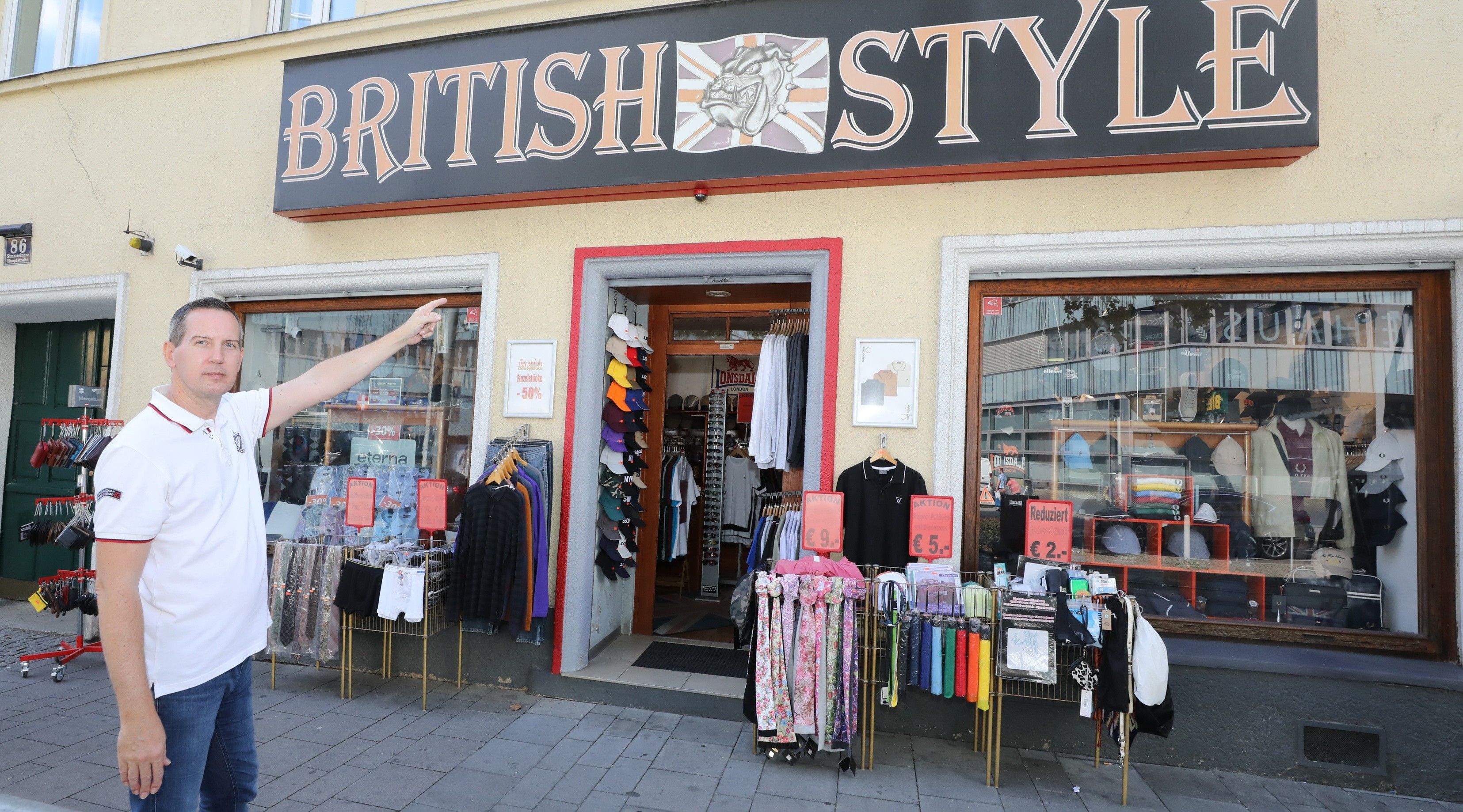 Eingangsbereich des Shops Britisch Style mti verschiedenen Kleidungsstücken wie Schals und Sonderangeboten davor.