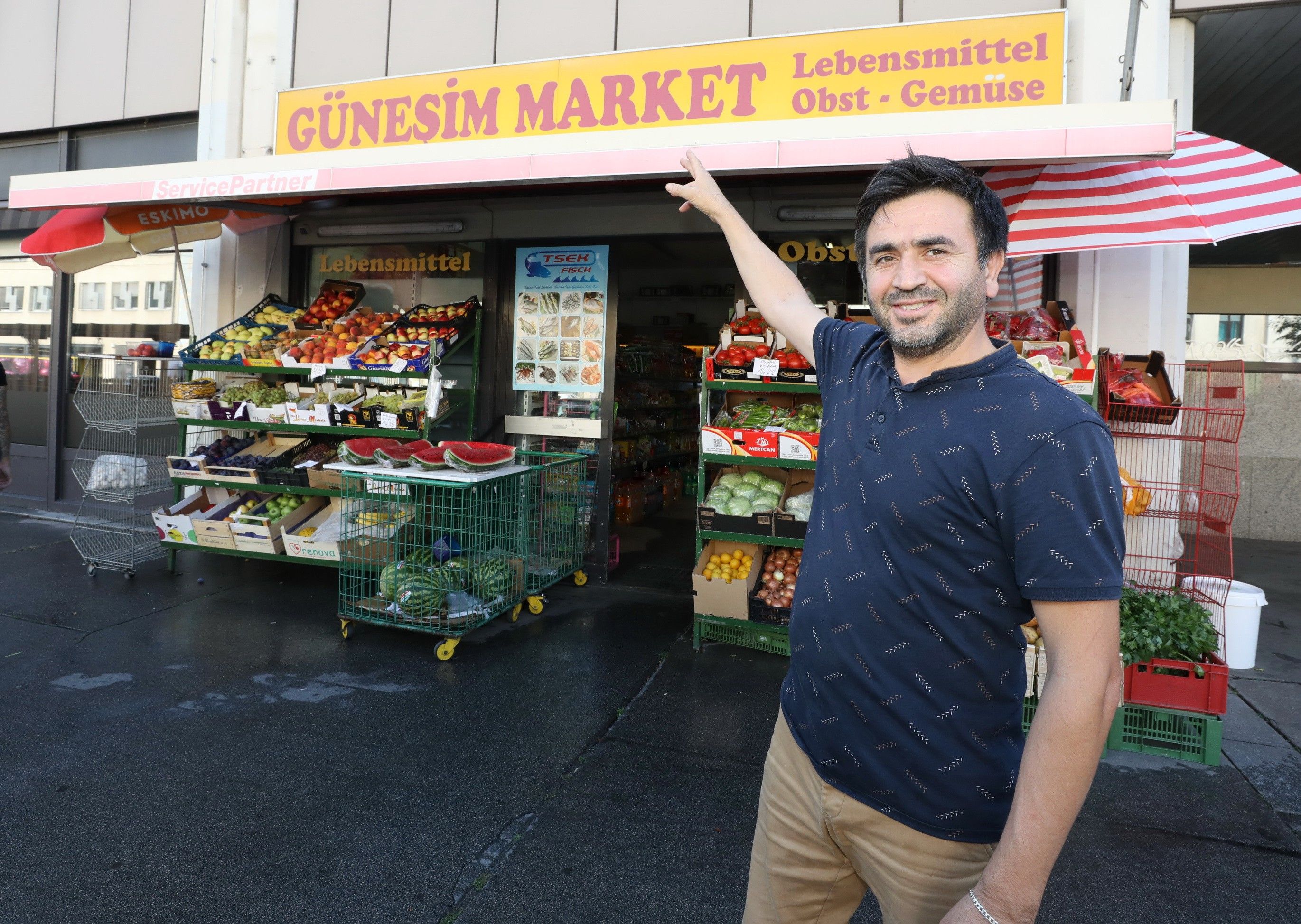 Bereich vor dem Günesim Market, Mann zeigt auf die rot gelbe Zeichnung oberhalb des Ladens