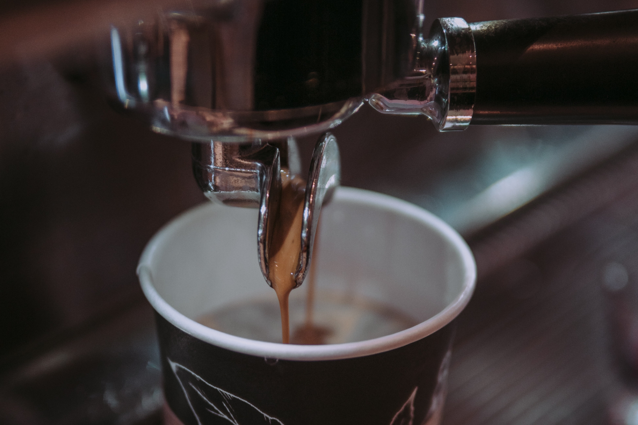 Zeigt einen Kaffeebecher wo gerade Kaffee reinrinnt