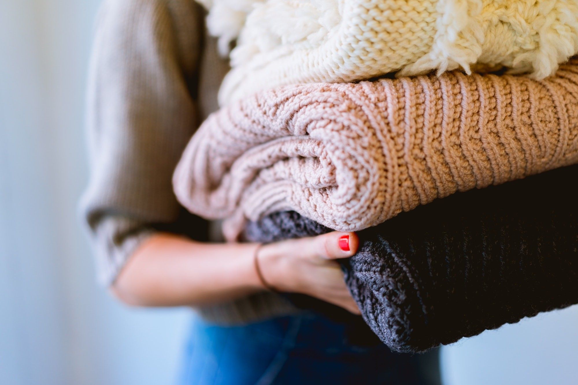 Eine Frau hält mehrere Wollpullover in der Hand