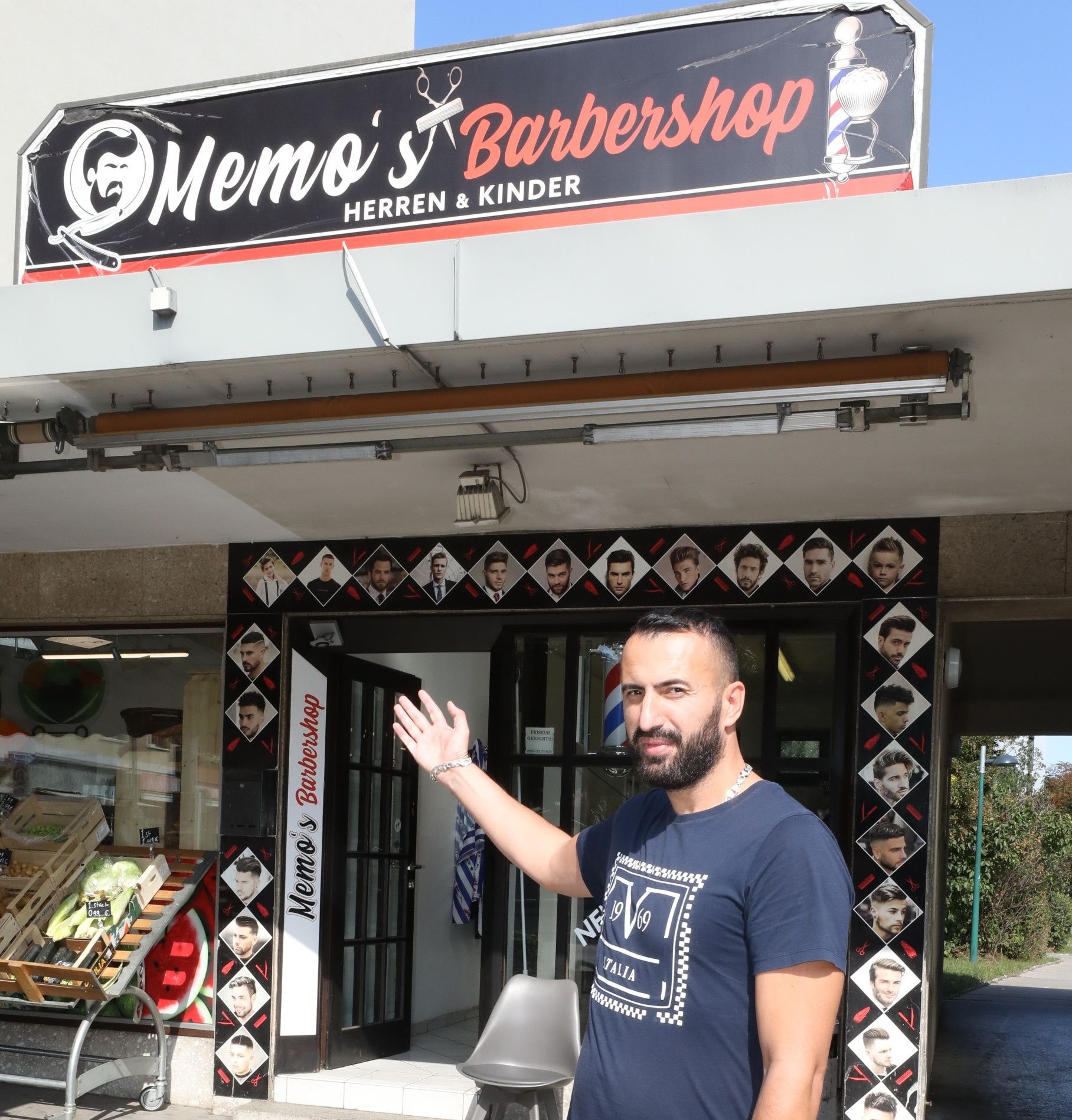 Eingangsbereich von Memo's Barbershop vor dem ein Mann auf den Eingang zeigt, der mit unterschiedlichen Modelbildern umrandet ist