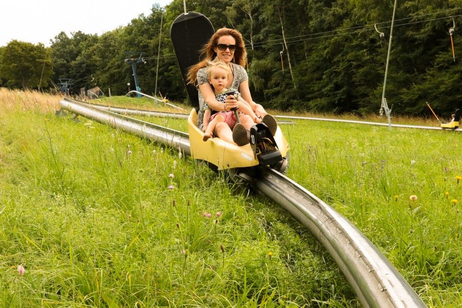 Eine Frau mit Kind sitzt in der Sommerrodelbahn auf der Hohen Wand Wiese