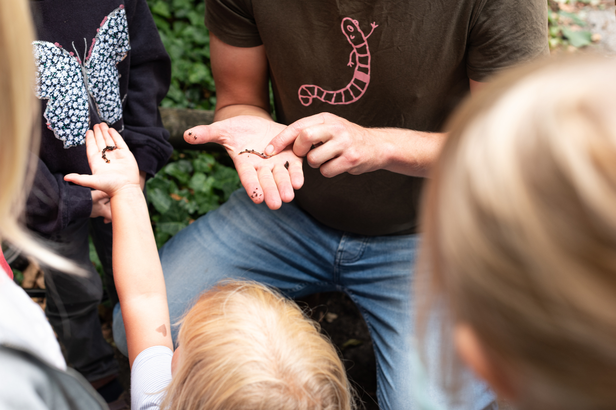 Foto: Eine Gruppe von Menschen mit einem Regewurm in einer Hand